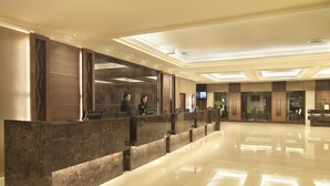 Ein Hotel-Rezeptionsbereich mit Marmorplatten, einer Glastrennwand und einem modernen Deckenstil.