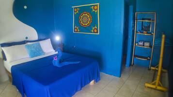 A room with a bed, a blue wall, a wooden ladder, and a shelf with decorative items.
