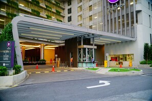 A hotel entrance with a modern design, including a covered walkway and a clear sign indicating "North & South Suites". - Homestay In The Heart of Kuala Lumpur at The Robertson KL (Kuala Lumpur)