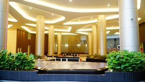 A modern lobby with a central water feature, large columns, and a seating area.