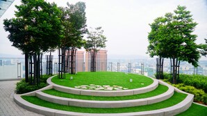 A landscaped garden with a central grassy area, stone steps, and trees.