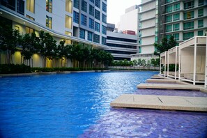 A swimming pool with steps leading into it, surrounded by modern buildings and trees. - Homestay In The Heart of Kuala Lumpur at The Robertson KL (Kuala Lumpur)