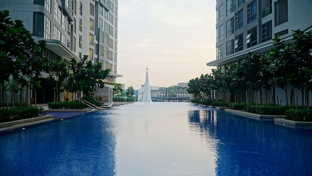 A swimming pool flanked by modern buildings with a central monument.