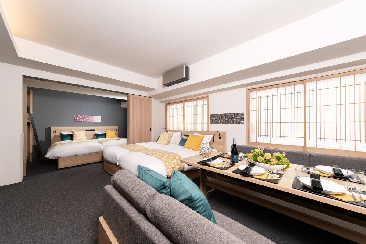 Una habitación de hotel moderna con una cama grande, un sofá y una mesa de comedor preparada para dos personas.