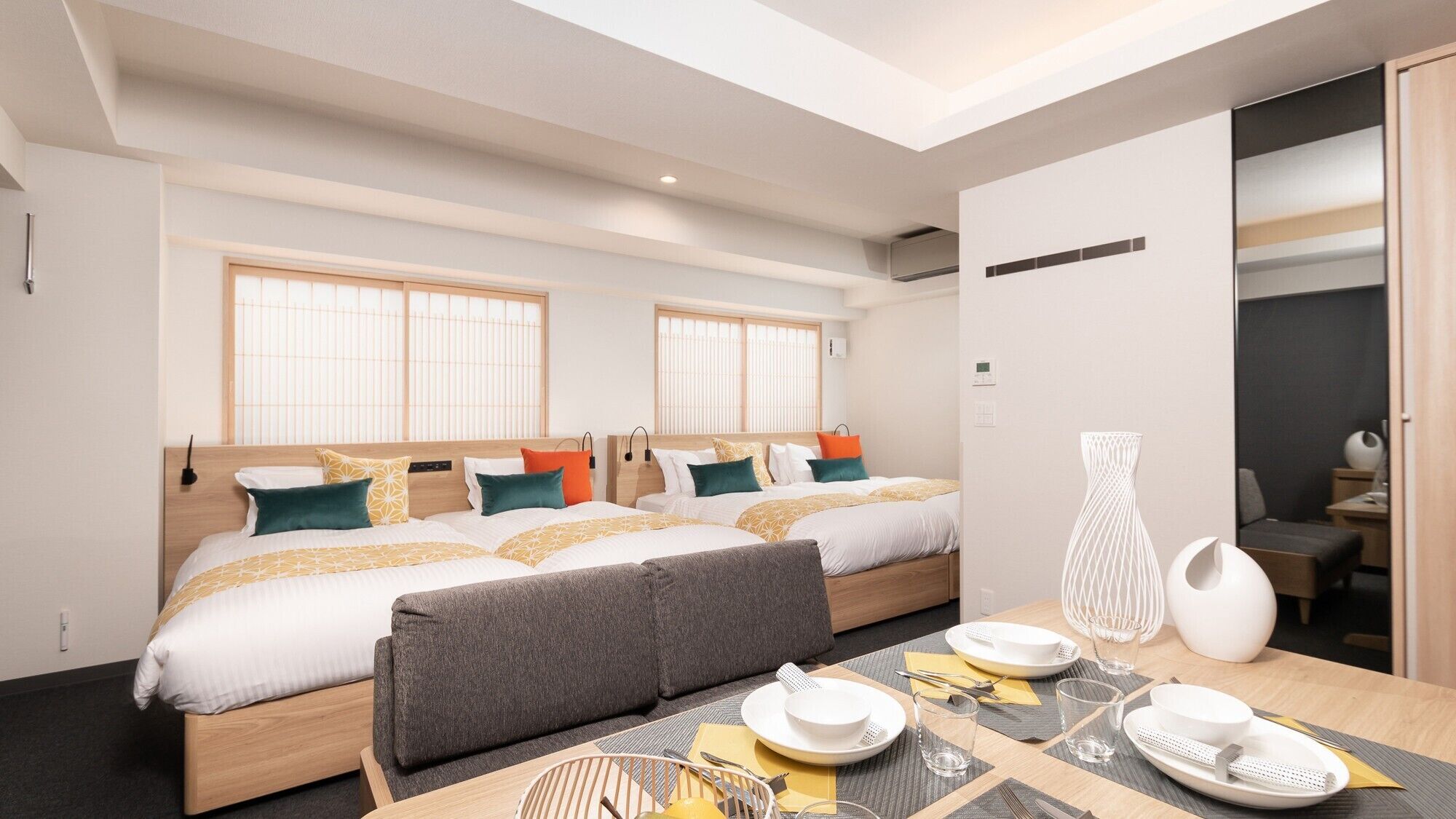 Una habitación de hotel moderna con dos camas, un comedor y vista a la ciudad.