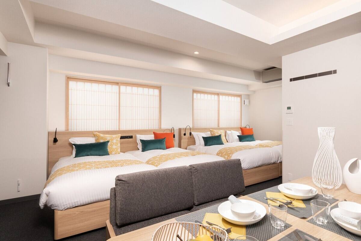 Una habitación de hotel moderna con dos camas, un comedor y vista a la ciudad.