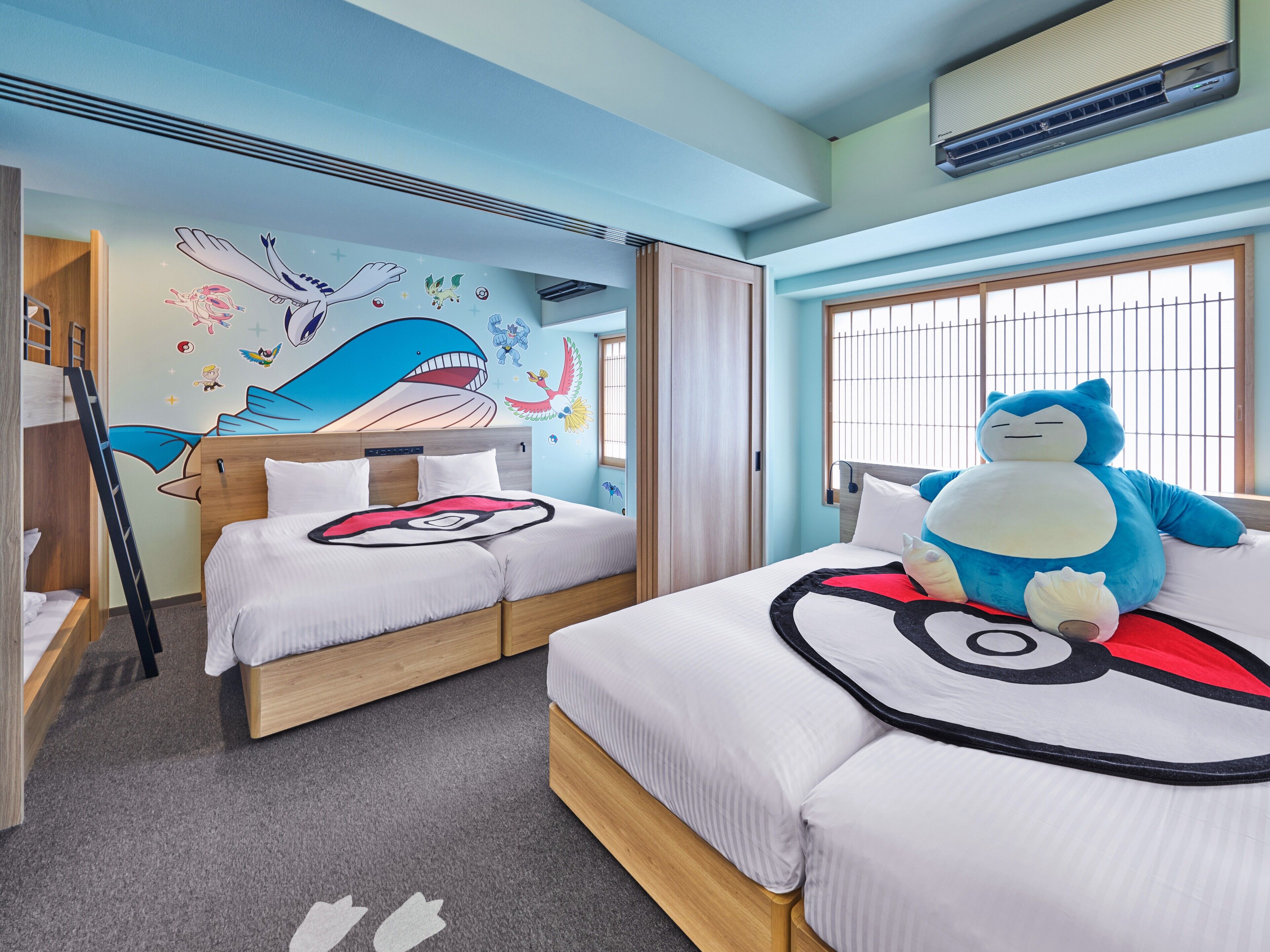 A hotel room with two beds, a large plush toy, and a mural on the wall.