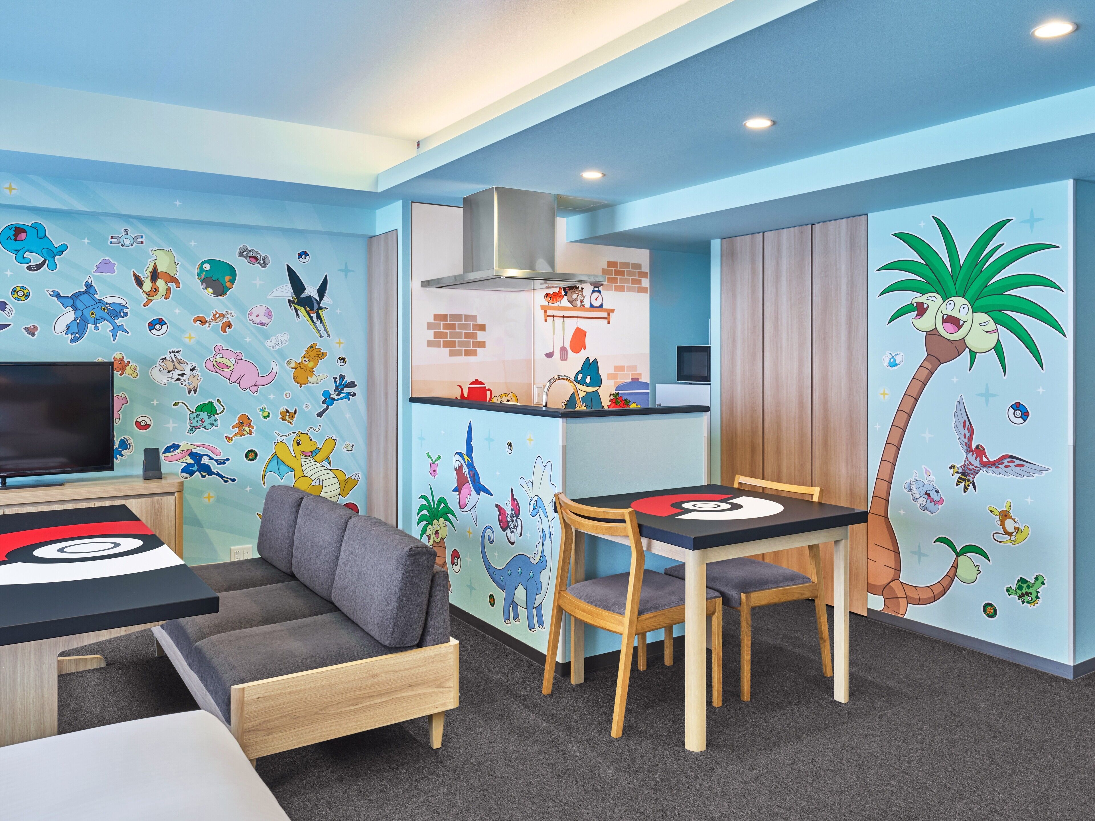 Une salle de jeux pour enfants avec un canapé, une table et des chaises, décorée avec des personnages de dessins animés.