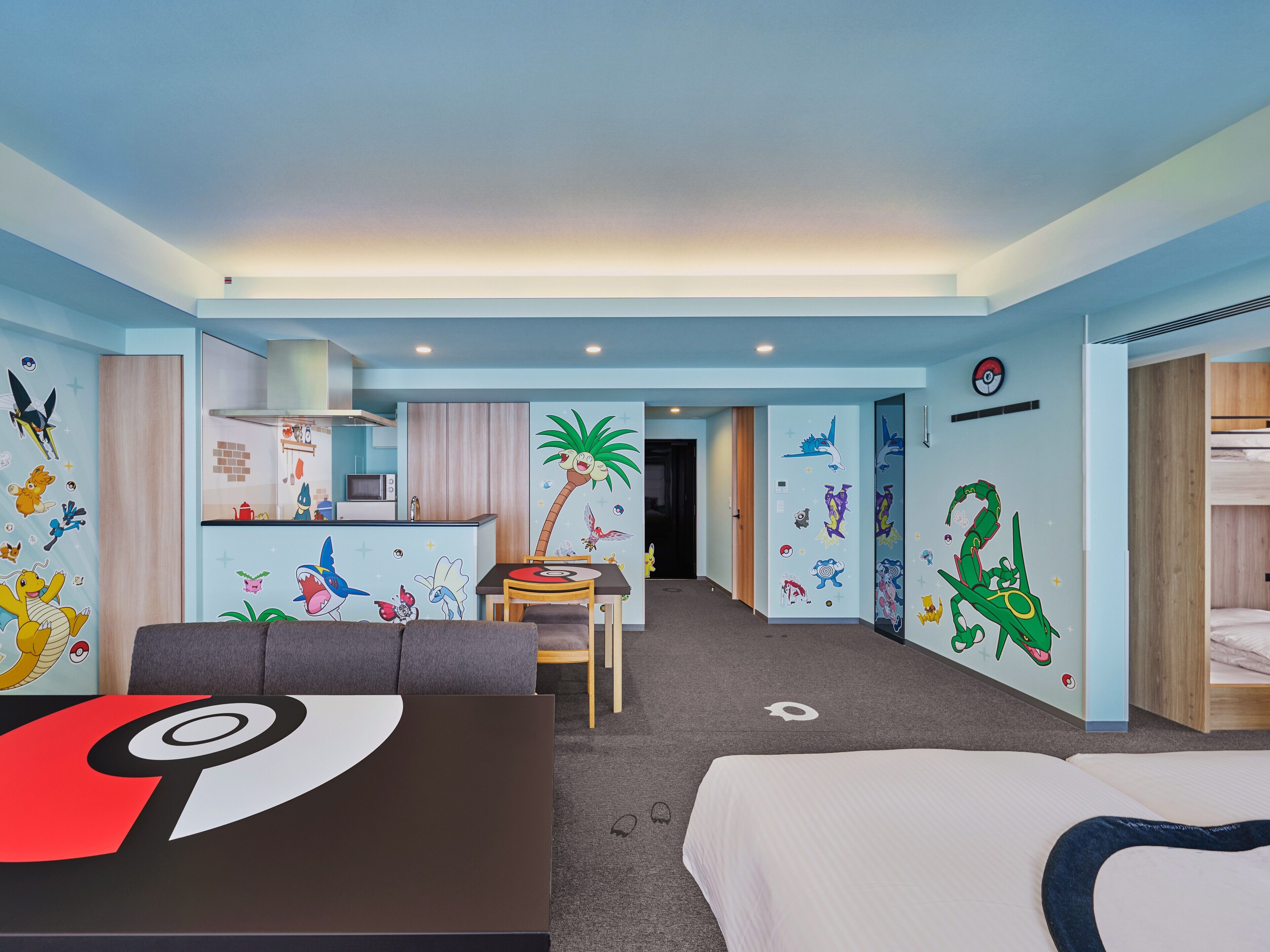 A hotel room with a kitchenette, a dining area, and a bunk bed.