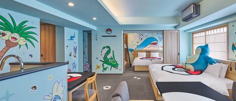Una habitación con una cama litera, un escritorio y una silla. Cuenta con decoraciones en la pared y una ventana con barrotes.
