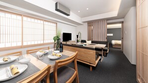 Un espace repas moderne avec une table en bois dressée pour quatre personnes, un canapé et un téléviseur.