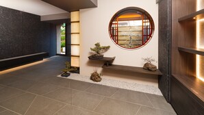 Un intérieur moderne avec une fenêtre circulaire, un banc et des plantes en pot.