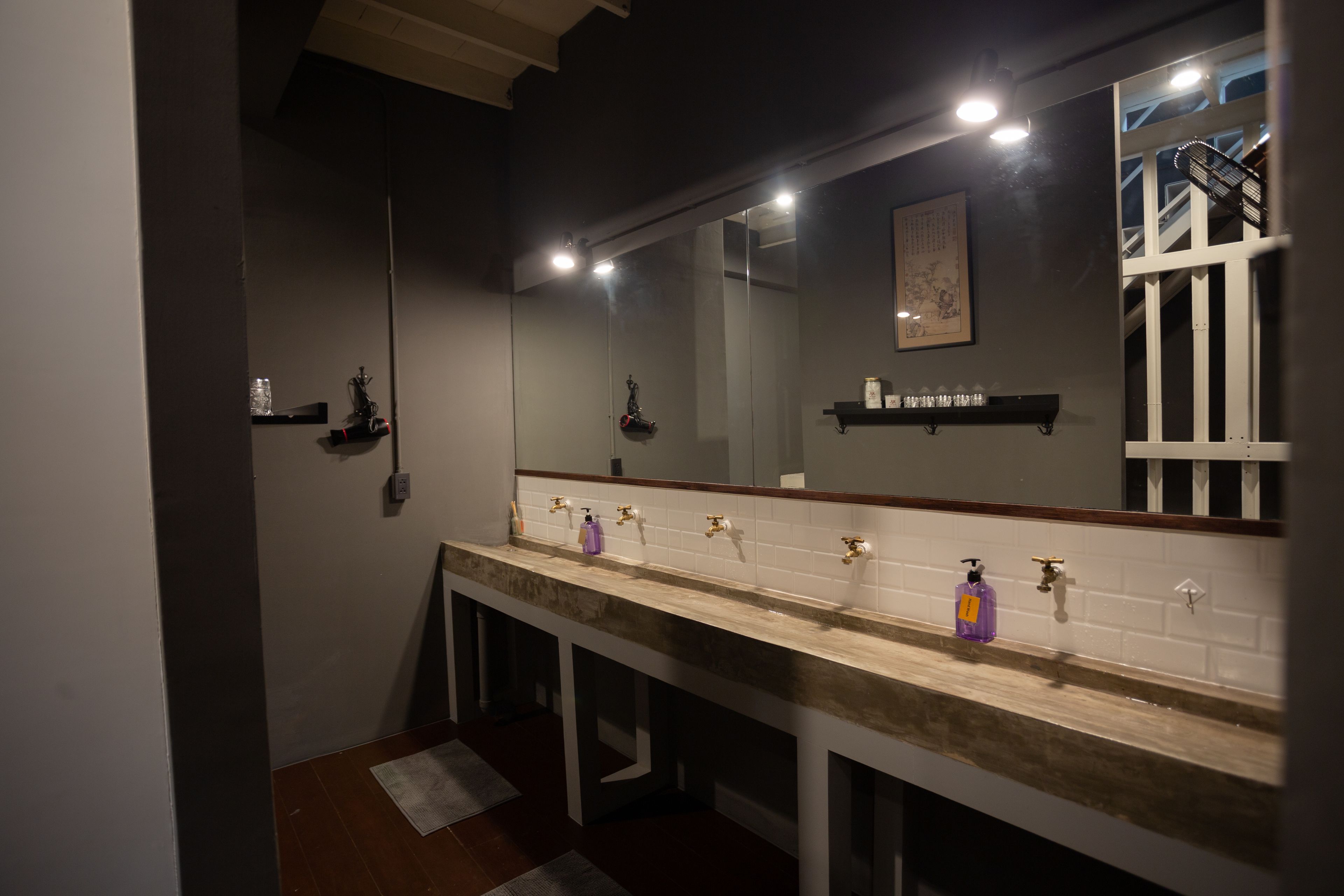 A modern bathroom with a long vanity, multiple sinks, and a large mirror.