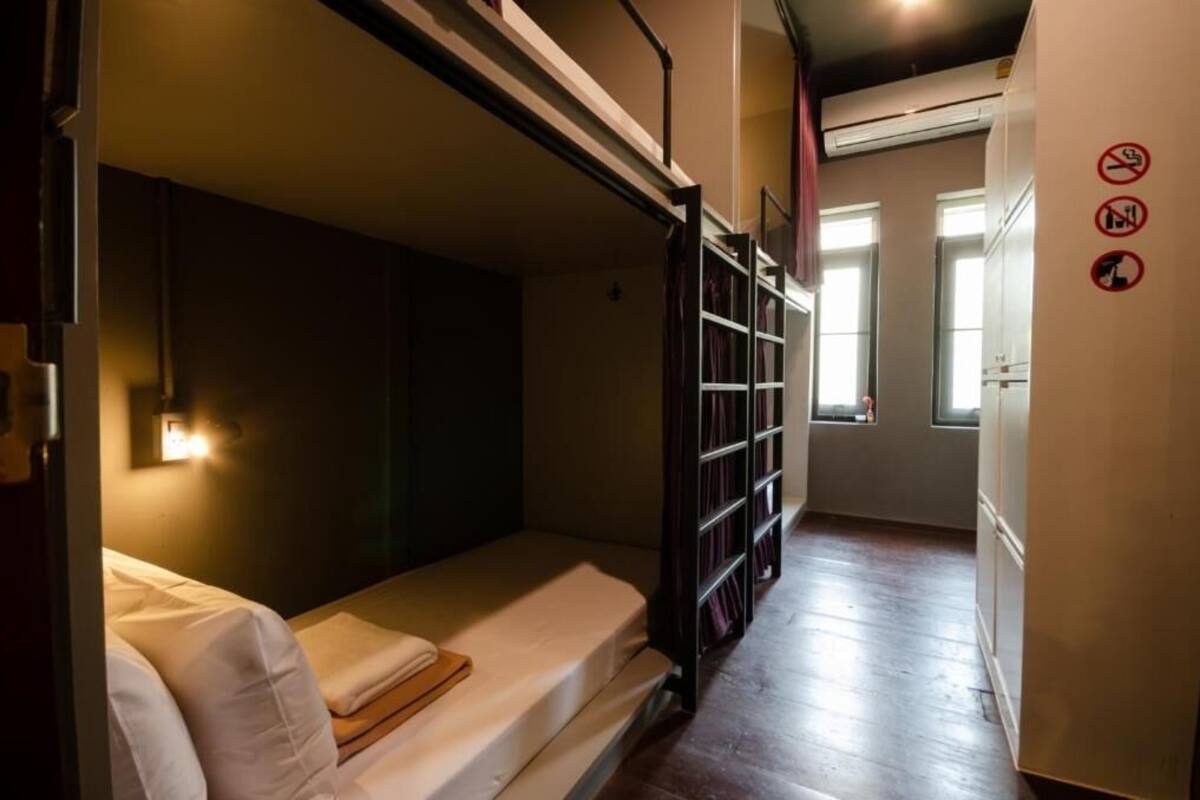 A compact room with a bunk bed, a small table, and a window.