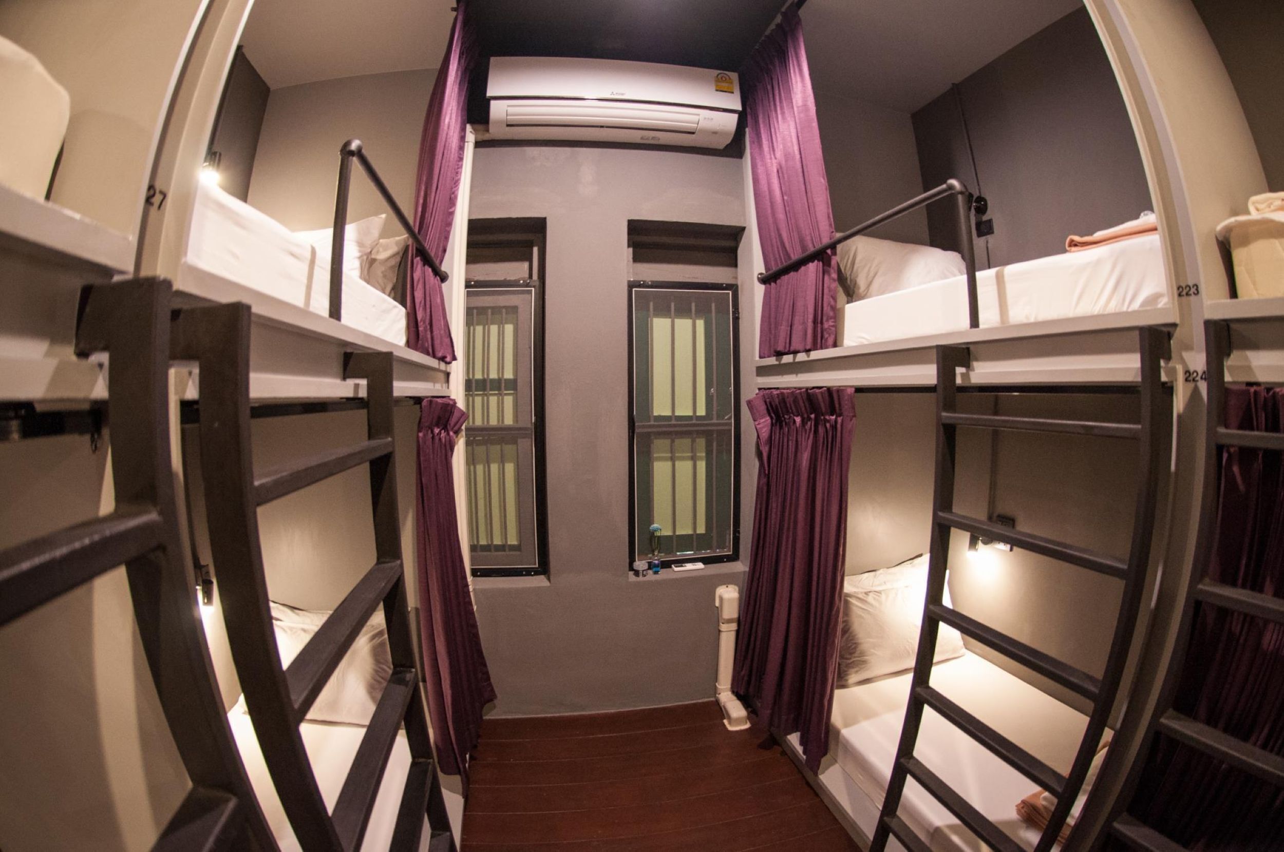 A bunk room with two beds, a window, and an air conditioning unit.