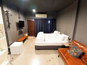 Hotellihuone, jossa on sänky, sohva, televisio, työpöytä ja ilmastointilaite.