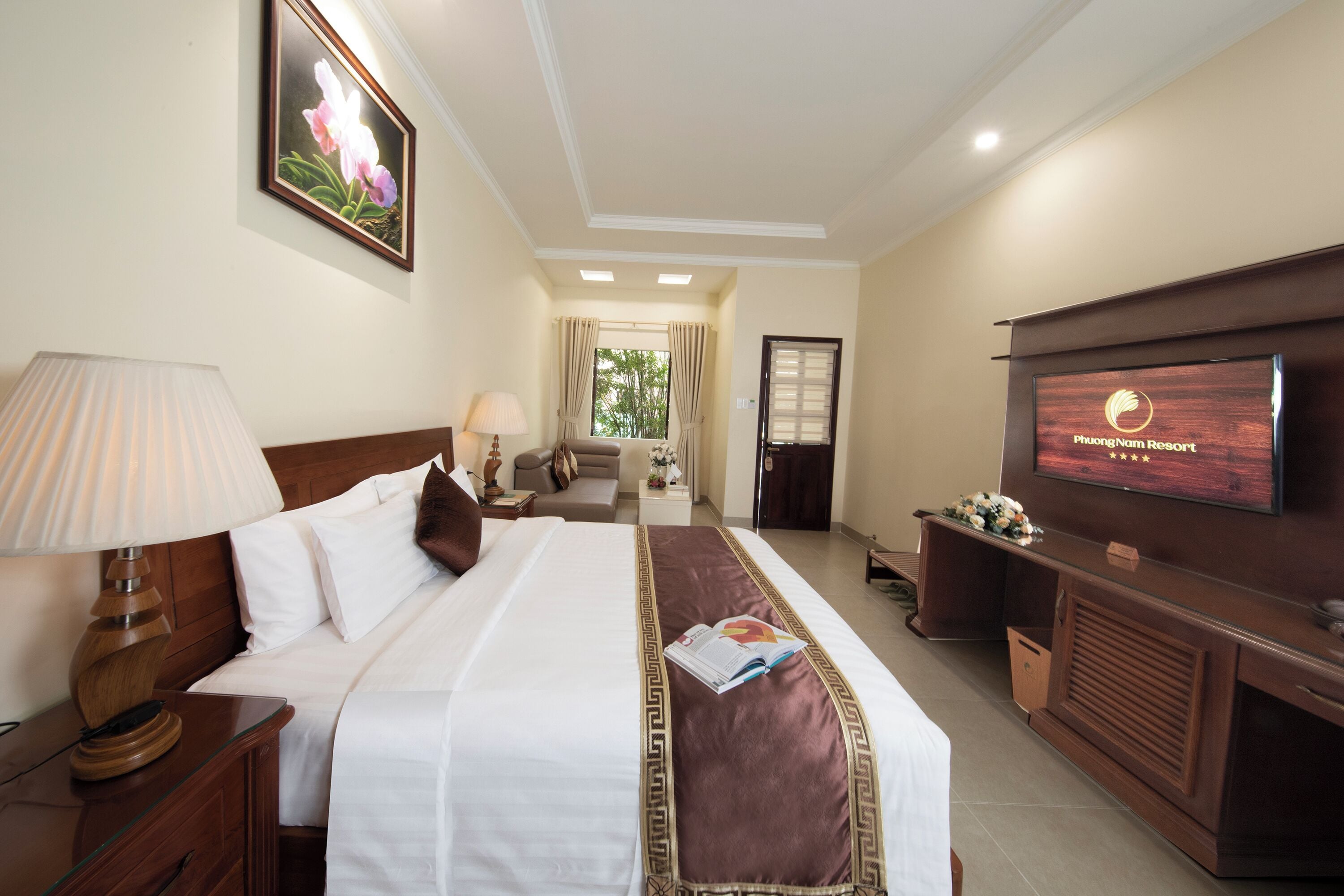 A hotel room with a large bed, a TV, a desk, and a window with curtains.