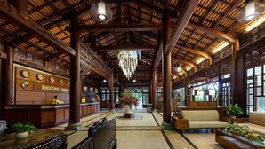 A traditional wooden lobby with a reception desk, clocks, and a seating area. - Phuong Nam Resort (Ho Chi Minh City)