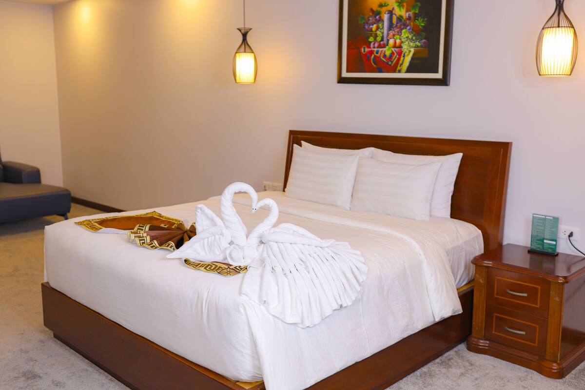 A neatly made bed with white linens and a decorative towel arrangement.