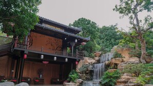 A traditional building with a tiled roof and a waterfall in the background. - Phuong Nam Resort (Ho Chi Minh City)