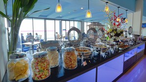 A buffet with various food items and a decorative vase with flowers. - Tanjung Kodok Beach Resort (Paciran)