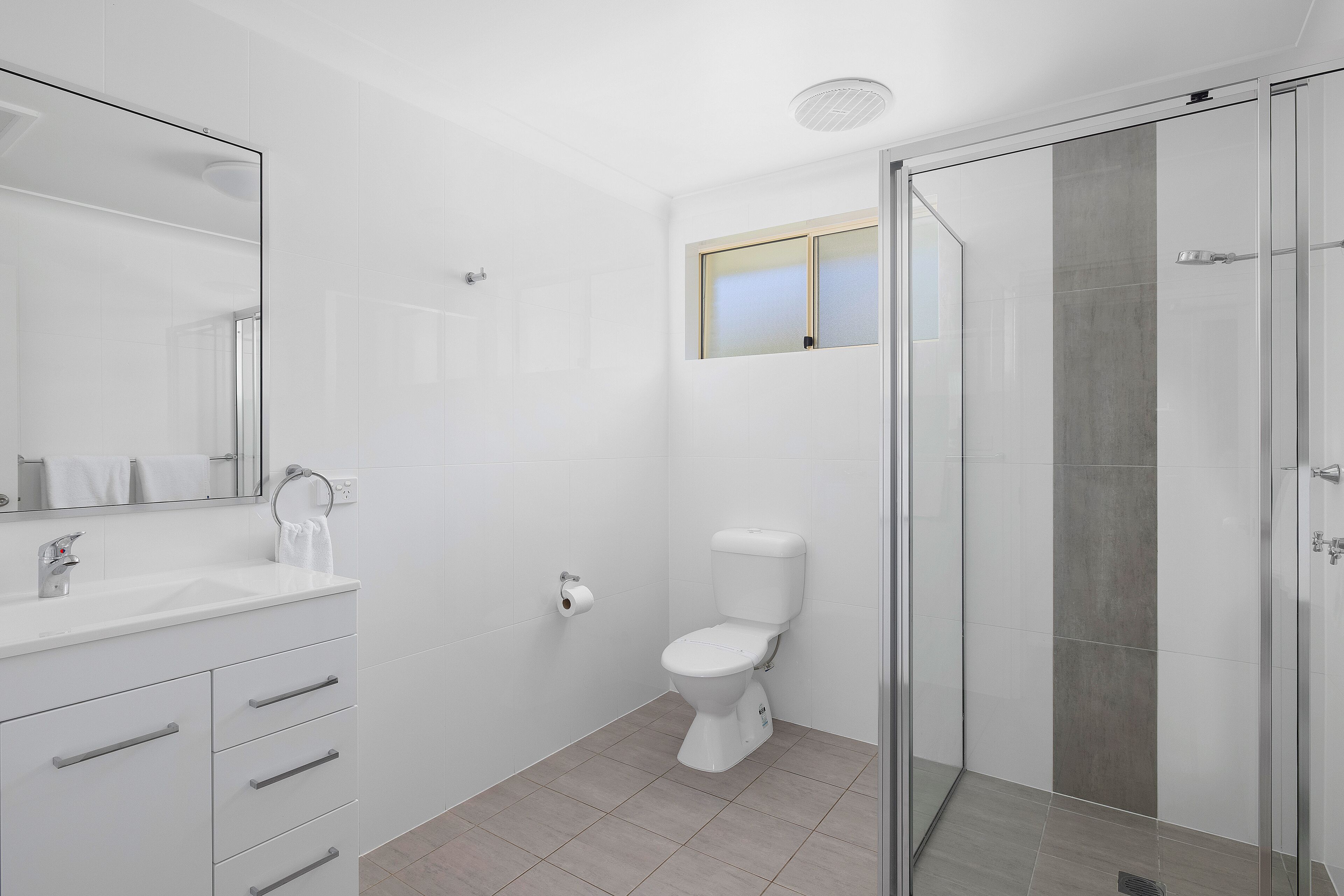 A modern bathroom with a glass shower enclosure, a white sink, and a toilet.
