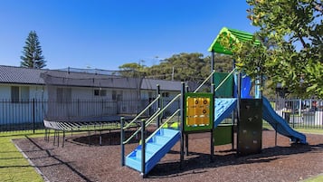 Une aire de jeux dotée d’un toboggan, d’un mur d’escalade et d’une structure avec un toit végétalisé.