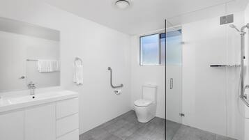 Un baño moderno con cabina de ducha de vidrio, un lavabo blanco y un inodoro.