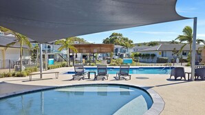 A swimming pool area with lounge chairs and a shaded canopy. - Seaside Holiday Resort Fingal Bay (Fingal Bay)