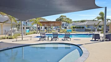 Relax by the serene pool surrounded by lounge chairs and a shaded seating area.
