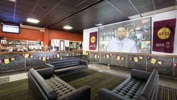 A bar area with seating and a large screen displaying a sports event.