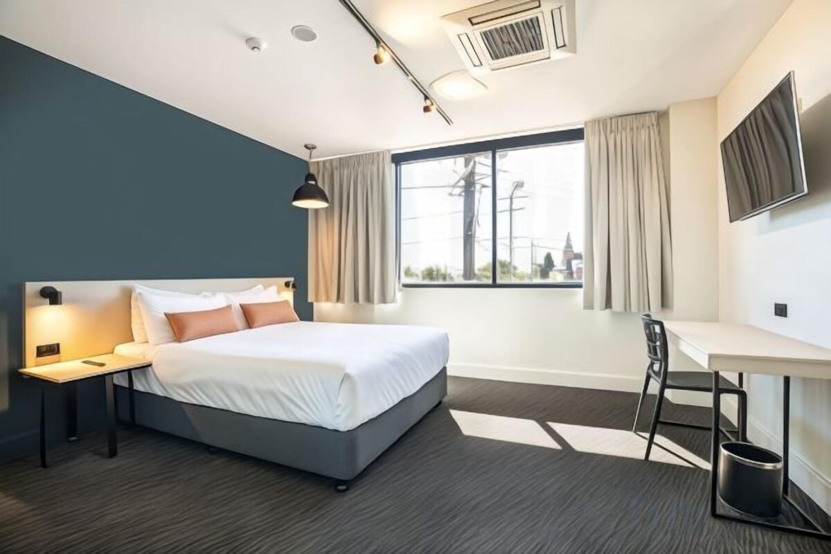 Habitación de hotel con cama, escritorio y ventana.
