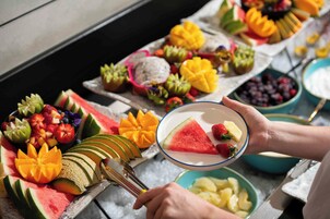 Une assiette de fruits coupés en tranches, accompagnée d’un bol de yaourt.