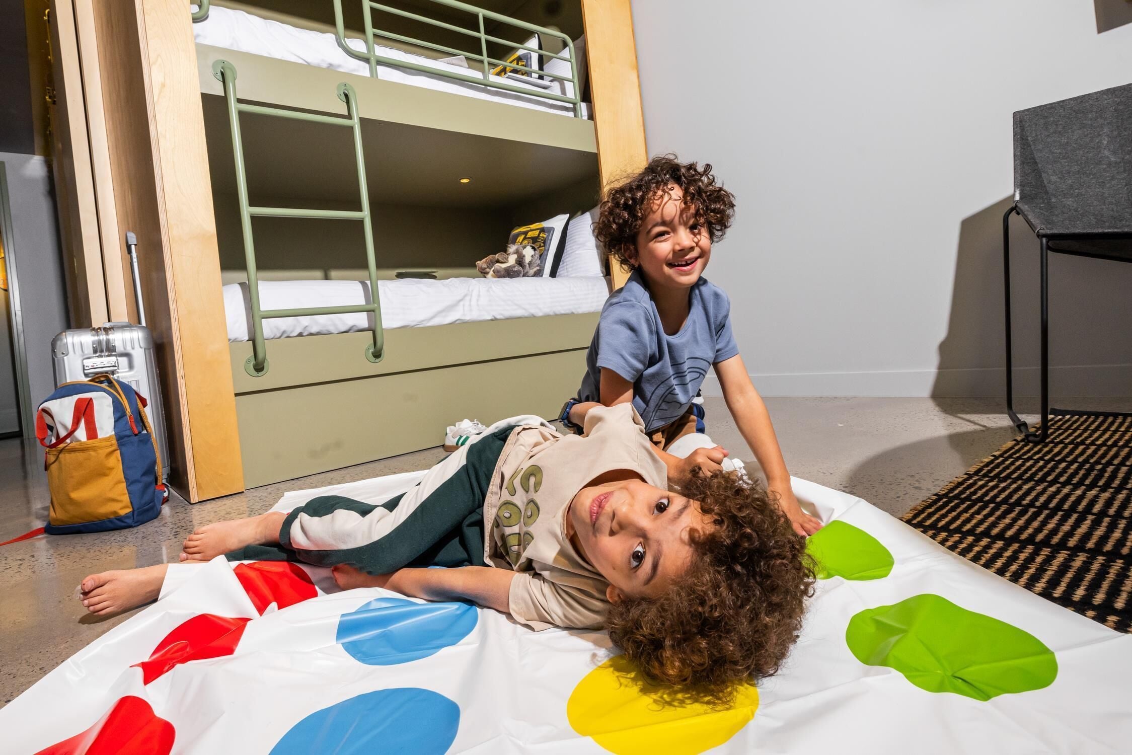 A bunk bed room with a suitcase and a backpack on the floor.
