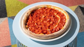 A pepperoni pizza on a white plate on a blue table.