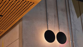 Un interior moderno con techo de madera perforada, pared de concreto y una lámpara circular.