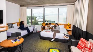 Habitación de hotel con dos camas, un escritorio, una silla y vistas a la ciudad.