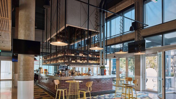A modern bar area with a bar counter, stools, and a patterned floor. - Atura Adelaide Airport (Adelaide Airport)