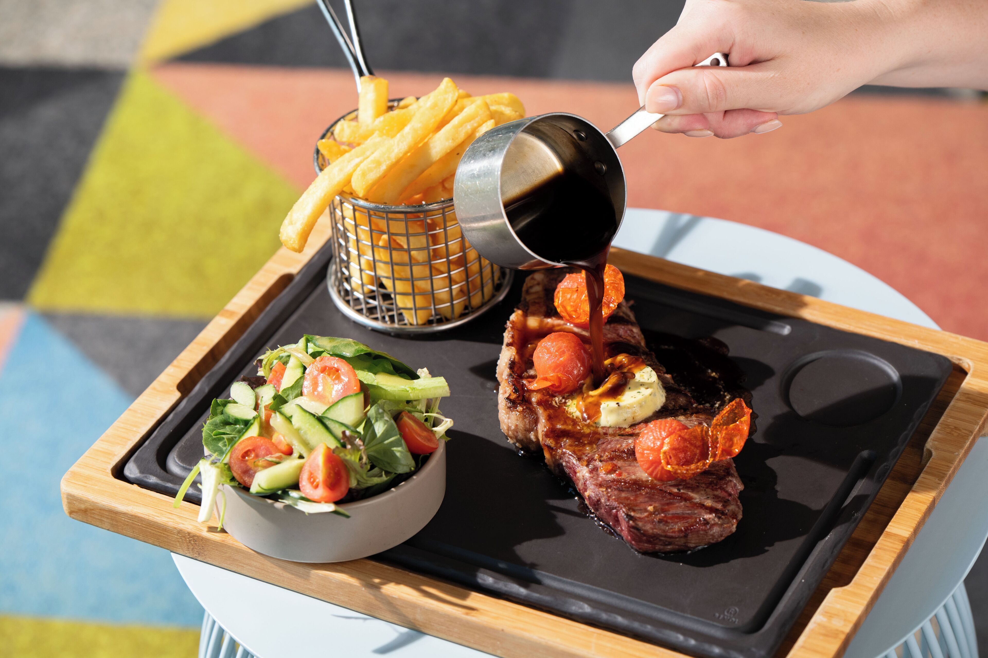 A tray with a steak, fries, and a salad.