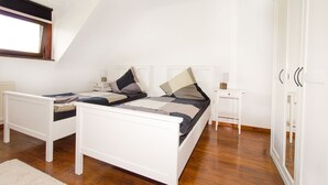 A bedroom with a bed, two bedside tables, a nightstand, a wardrobe, and a window. - Ferienwohnung BECKENDORF (Losheim am See)