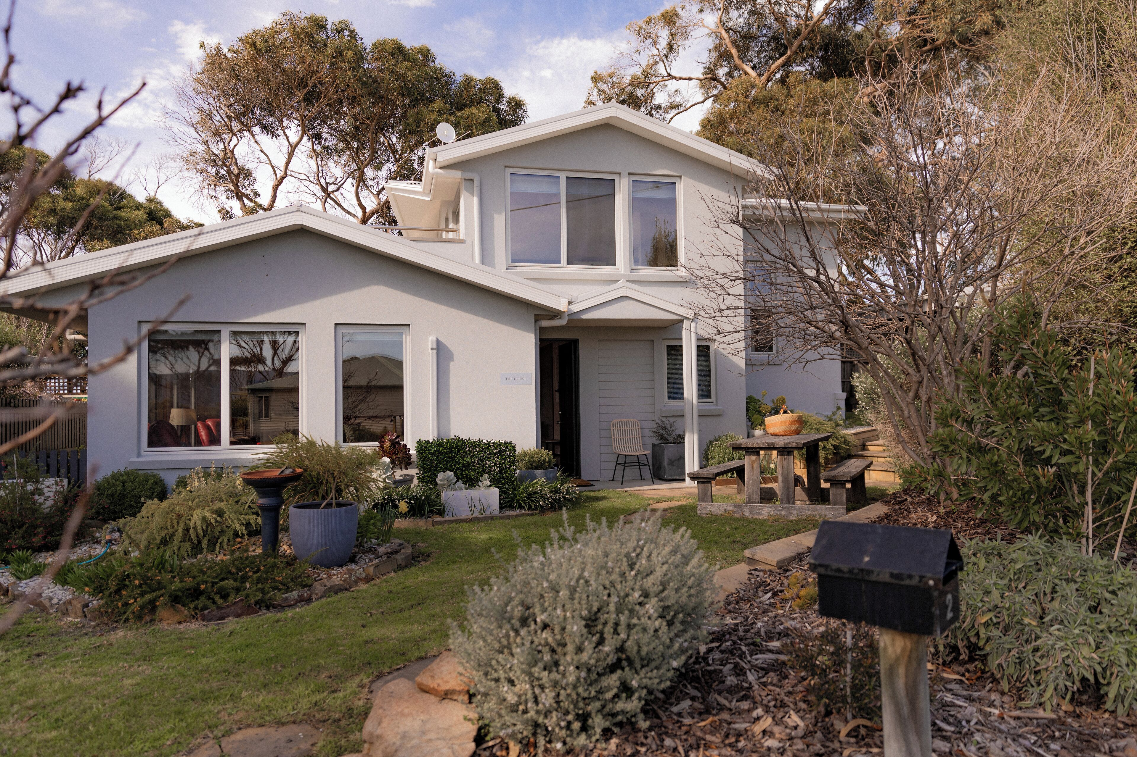 A two-story house with a front porch, a garage, and a well-maintained garden.