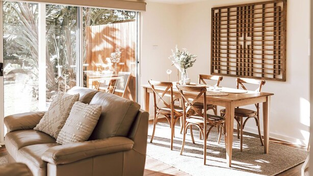 Ein modernes Wohnzimmer mit einer Ledersofa, einem Holzesstisch und Stühlen.