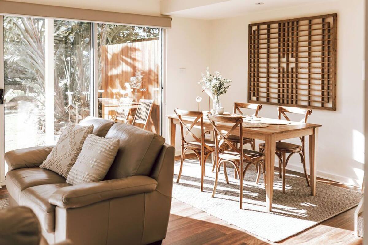 A modern living room with a leather sofa, wooden dining table, and chairs.
