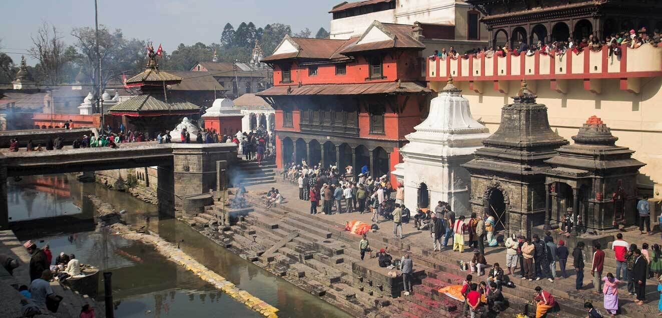 Una zona ribereña concurrida con arquitectura tradicional, que incluye templos y un puente.