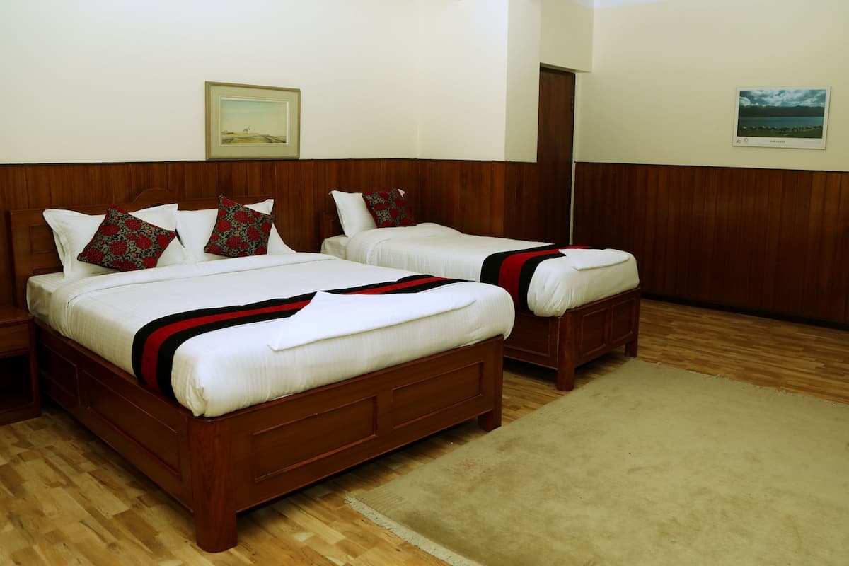 A double bed with a wooden headboard, two bedside tables, a beige carpet, and a framed picture on the wall.