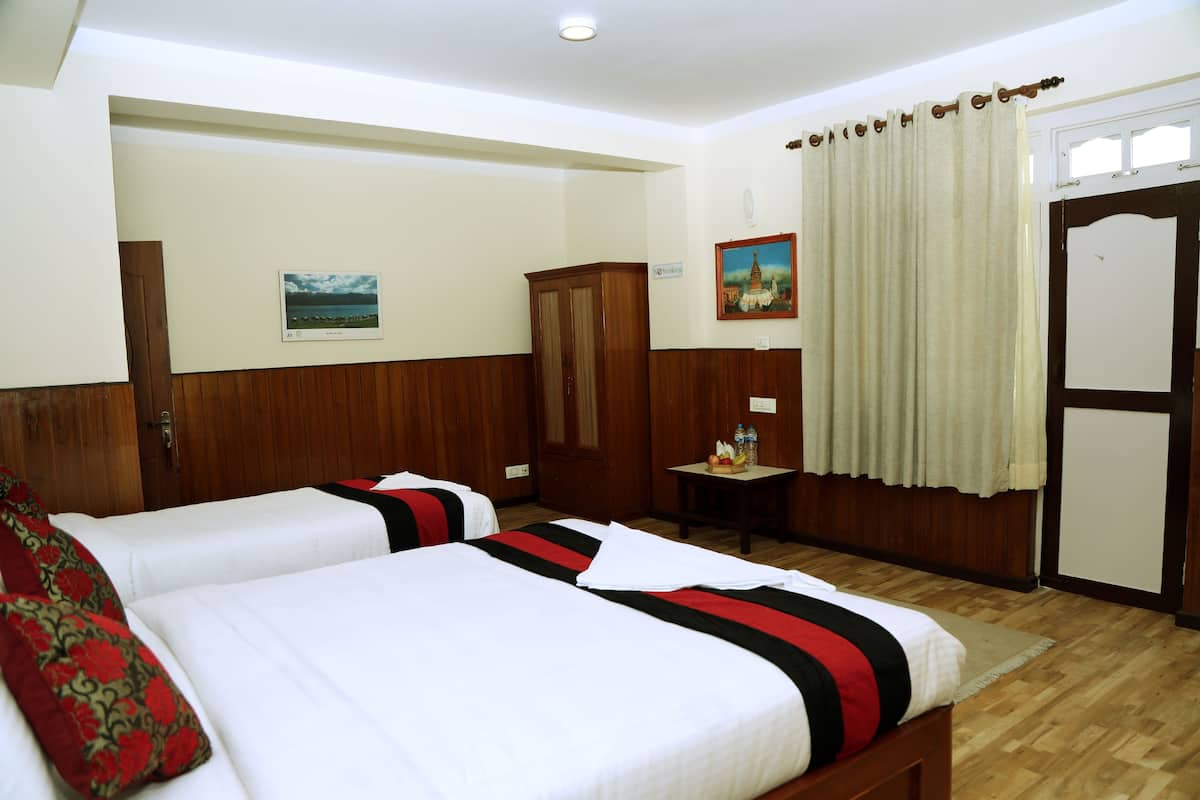 A hotel room with two beds, wooden paneling, a small table with a bottle, and a painting on the wall.