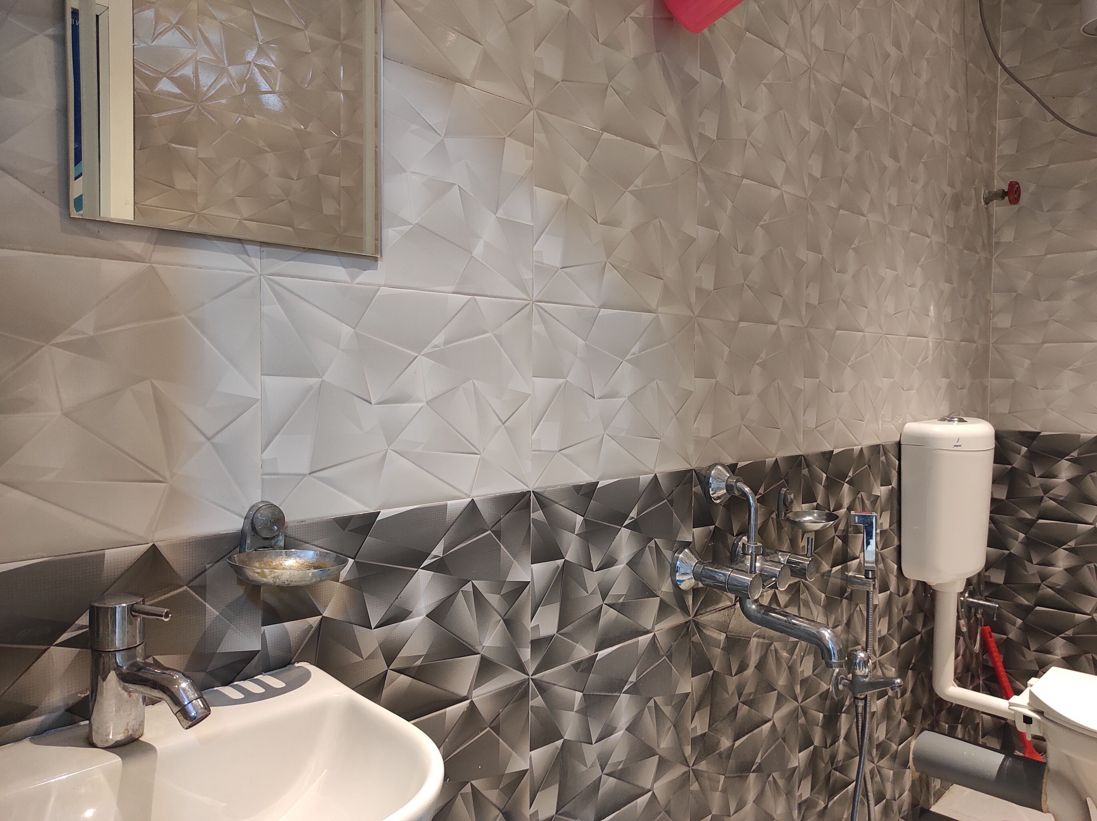 A bathroom with a sink, mirror, and a toilet.