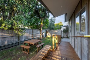 Una terraza de madera con mesas de picnic y una pérgola.