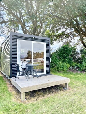 A modern, compact cabin with a deck and outdoor seating area. - Athenree Hot Springs & Holiday Park (Waihi Beach)