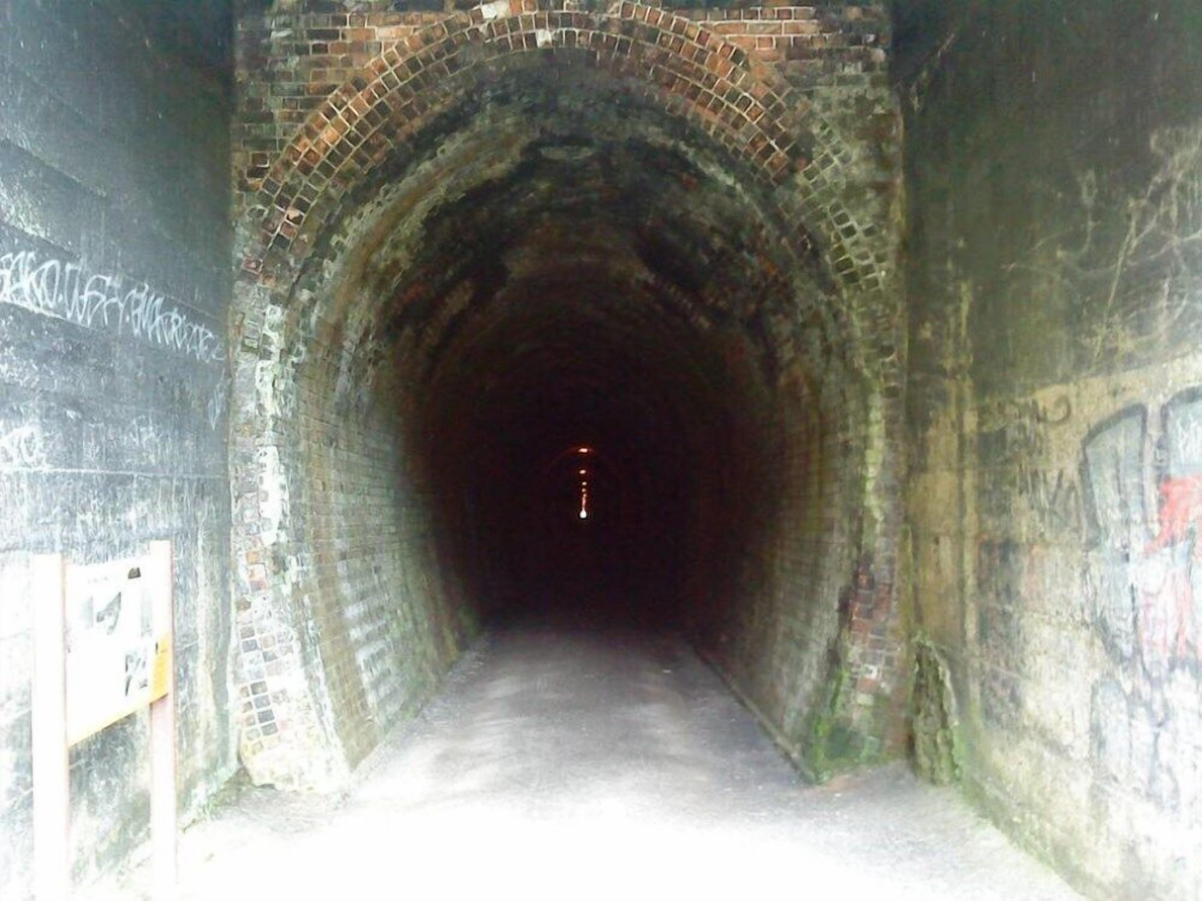 A tunnel with brick walls and graffiti.